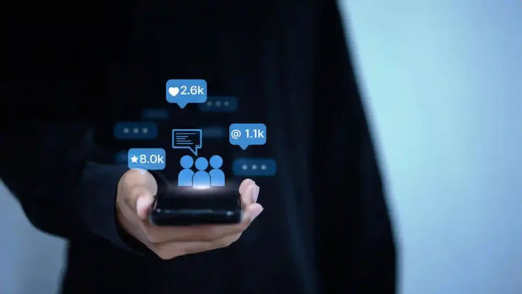 Hands holding a smartphone with floating social metrics (likes, followers) around the screen, illustrating social engagement.