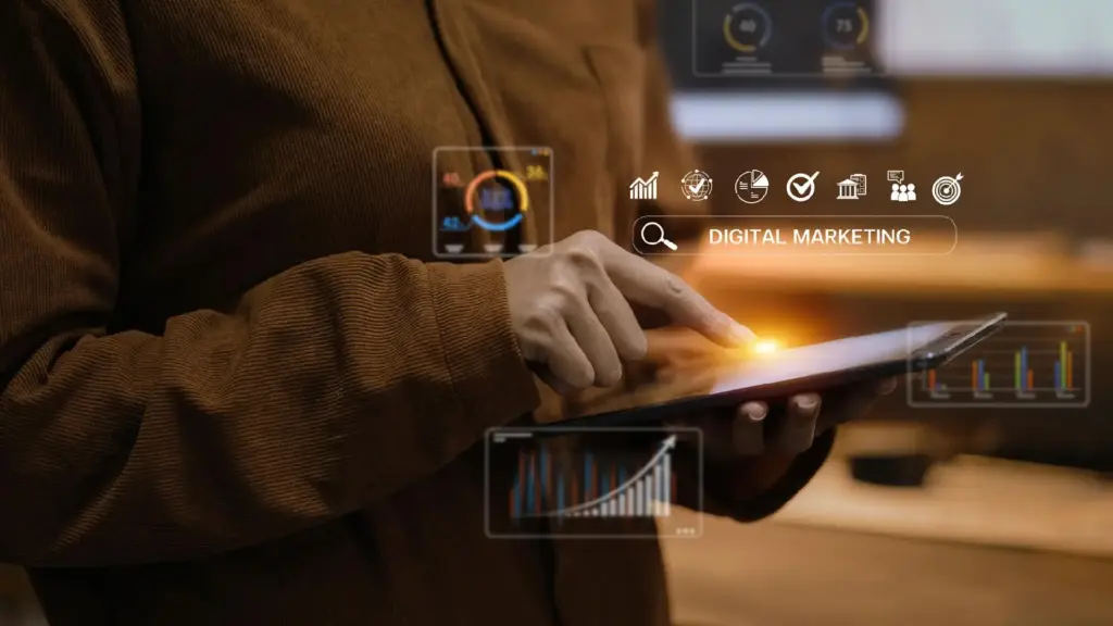 Person holds a tablet with glowing digital marketing icons and the label DIGITAL MARKETING, tapping the screen.