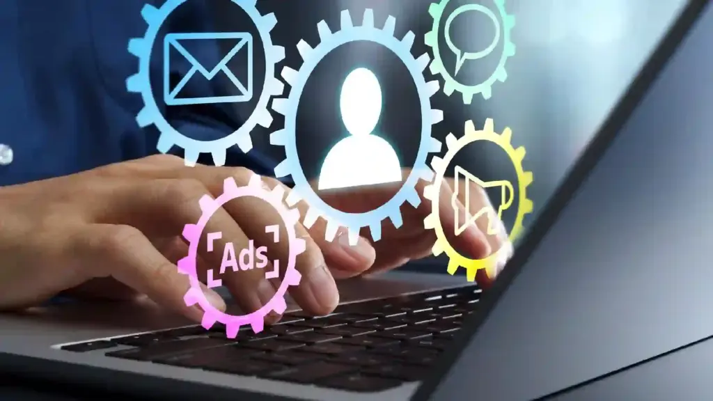 Hands typing on a laptop with colorful gear icons (email, chat, ads) symbolizing digital marketing automation and user interaction.