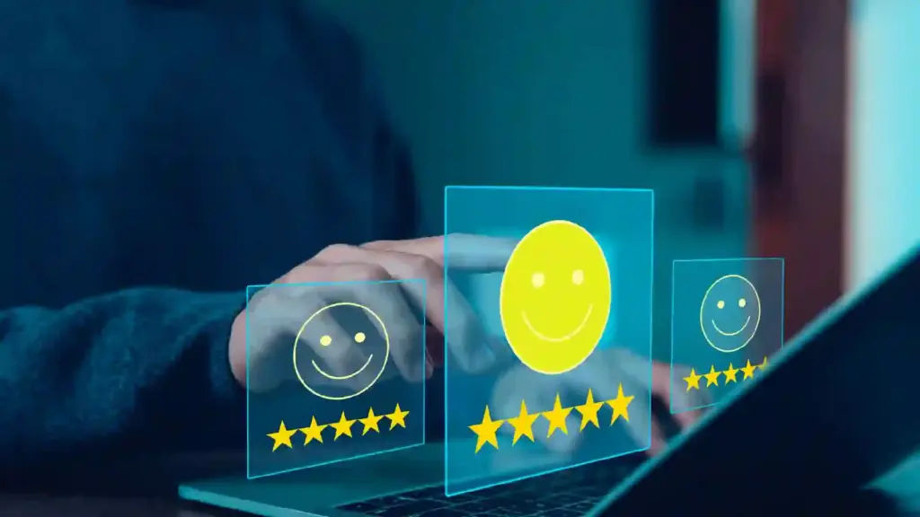 Hand interacts with holographic rating panels showing smiley faces and 5-star ratings above a laptop, in a dark room.