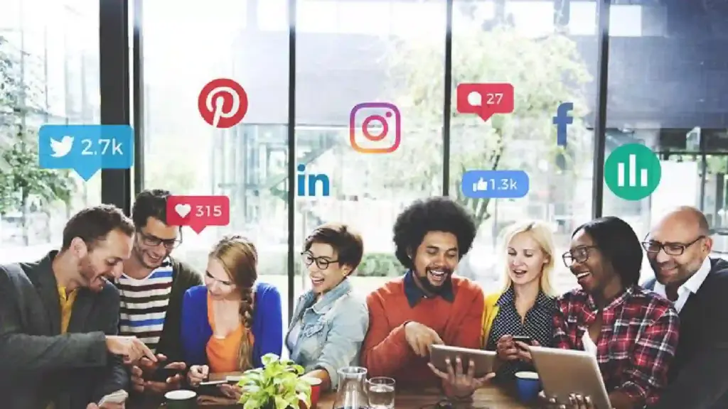 New Project - 2026-06-22T151359477 - Brill Creations Diverse group of coworkers around a table, with colorful social media icons (Twitter, LinkedIn, Instagram, Pinterest, Facebook) in the background.