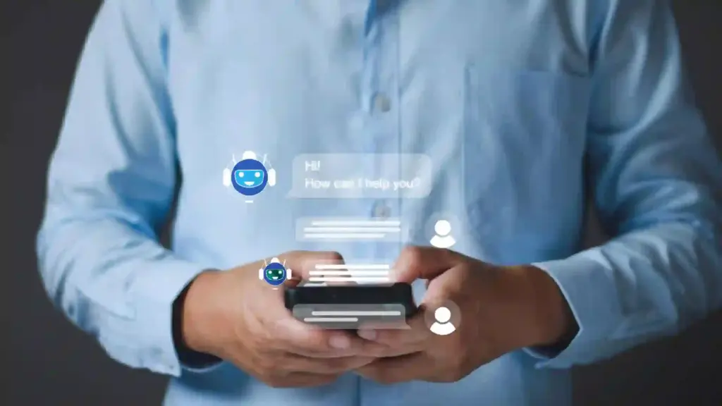 Person in a blue shirt holds a smartphone with translucent holographic chat bubbles, including a smiling robot icon and a greeting message that says, 'Hi! How can I help you?'