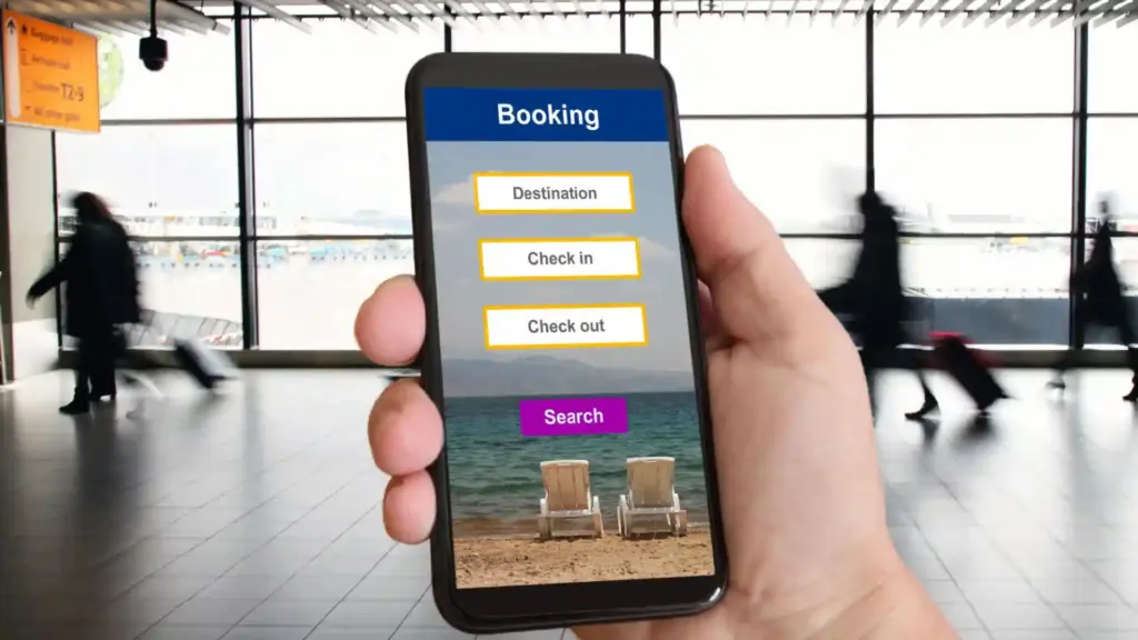 Hand holding a smartphone showing a travel booking app with Destination, Check in, Check out options and a purple Search button; blurred airport terminal in the background.